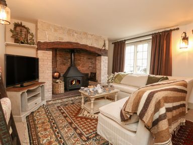 A living room with a stone fireplace wood stove sofas curtains and a coffee table at Norden House in Maiden Newton