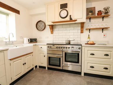 A kitchen with a stove sink toaster kettle and shelves with glasses at Norden House in Maiden Newton
