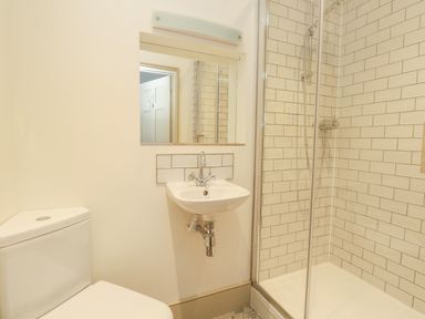 A bathroom with a toilet a sink and a shower with tiled walls at Norden House in Maiden Newton