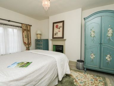 A bedroom with a bed a dresser a wardrobe and a framed flower picture at Norden House in Maiden Newton