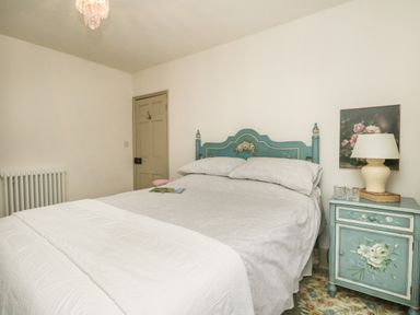 A bedroom with a bed with floral headboard and matching bedside table with a lamp at Norden House in Maiden Newton