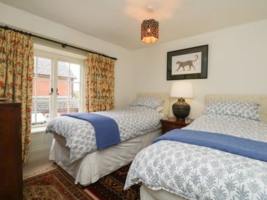 A bedroom with two single beds a lamp and a framed picture above a bedside table at Norden House in Maiden Newton