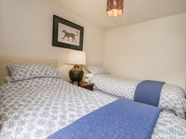 A bedroom with two beds a nightstand lamp and a leopard picture on the wall at Norden House in Maiden Newton