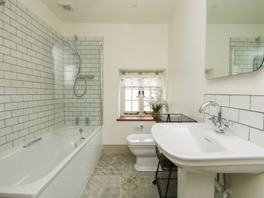 A bathroom with a bathtub shower toilet sink and a small window at Norden House in Maiden Newton