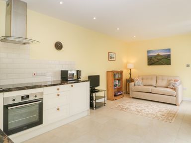 A kitchen and living area with a sofa and a bookcase at Long Batch Cottage in Ditcheat