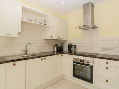A kitchen with white cabinets a stainless steel sink an oven and appliances at Long Batch Cottage in Ditcheat