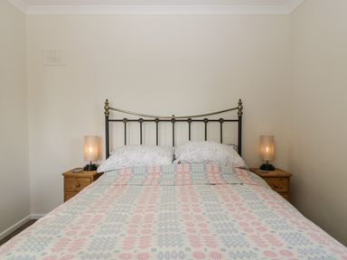 A bedroom with a bed between two wooden nightstands each with a lamp at Long Batch Cottage in Ditcheat
