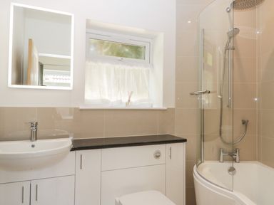 A bathroom with a sink a mirror a frosted window a bathtub with a shower at Long Batch Cottage in Ditcheat