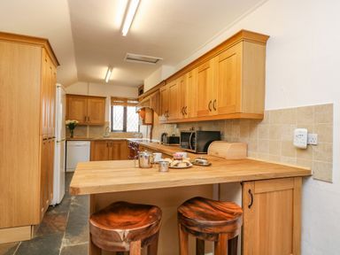 A kitchen with wooden cabinets stools and countertop with a plate of snacks and drinks at South Boduel Farmhouse in Liskeard