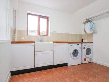 A laundry room with a washing machine dryer sink and window at South Boduel Farmhouse in Liskeard
