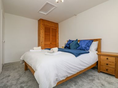 A bedroom with a bed with blue pillows and a wooden nightstand at South Boduel Farmhouse in Liskeard