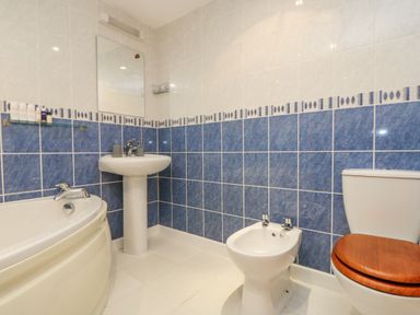 A bathroom with a bathtub sink bidet and toilet with a wooden seat cover at South Boduel Farmhouse in Liskeard