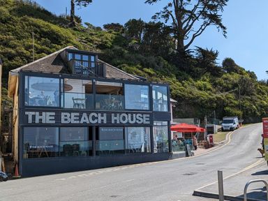 A two story building named The Beach House with glass windows and outdoor seating at Keepers Cottage in Liskeard