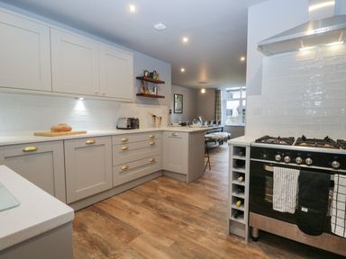 A kitchen with grey cabinets a stove countertop and dining area at Raybarrow in Windermere