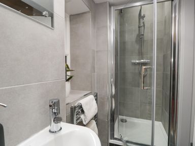 A bathroom with a sink faucet a glass shower enclosure and a towel hanging on a rack at Raybarrow in Windermere