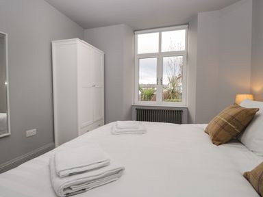 A bedroom with a bed, pillows, towels, a wardrobe, a window, and a lamp at Raybarrow in Windermere