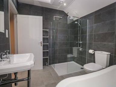 A bathroom with a shower area a toilet a sink and a white door at Raybarrow in Windermere