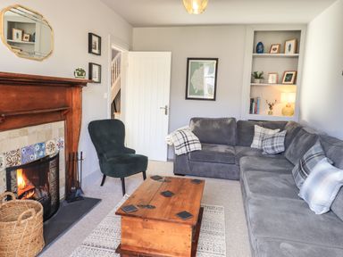A sitting room with a fireplace a wooden coffee table and a grey corner sofa at Raybarrow in Windermere