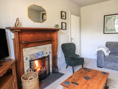 A living room with a wooden fireplace a green armchair and a wooden coffee table at Raybarrow in Windermere