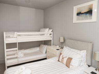 A bedroom with a double bed and bunk beds a nightstand with a lamp and a framed picture on the wall at Raybarrow in Windermere