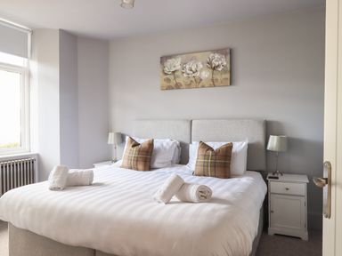 A bedroom with a double bed two bedside tables and a window at Raybarrow in Windermere