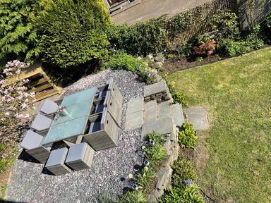 A garden with a patio table and chairs surrounded by plants and a lawn at Raybarrow in Windermere