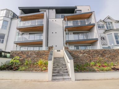 The front view of a modern apartment building with balconies stone walls and a central staircase at Onshore in Newquay
