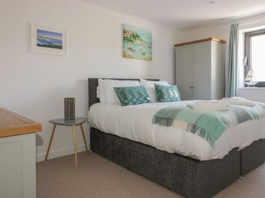 A bedroom with a double bed two teal pillows and a teal throw blanket at Onshore in Newquay