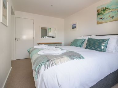 A bedroom with a double bed green pillows and folded towels on the bed at Onshore in Newquay