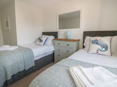 A bedroom with two single beds a chest of drawers with a lamp and a mirror at Onshore in Newquay