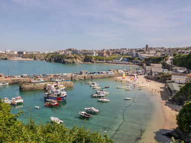 A harbor with boats docked and a sandy beach with people near Onshore in Newquay