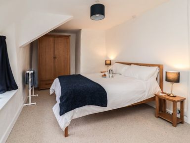 A bedroom with a double bed wooden wardrobe bedside tables and lamps at Lavender Cottage in South Zeal