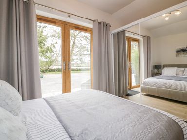 A bedroom with a bed near wooden framed double glass doors and mirrored wardrobe at Westfields in Kennards House near Launceston