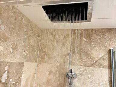 A shower with a ceiling rain shower head and a handheld shower head in a tiled bathroom at Westfields in Kennards House near Launceston