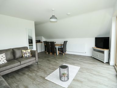A living room with a sofa dining table chairs and television at The Attic in Blackborough End near Kings Lynn