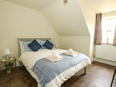 A bedroom with a bed with blue pillows and a blue throw on the bed at The Attic in Blackborough End near King's Lynn