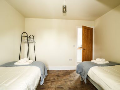 A bedroom with two single beds with blankets and towels and a wooden door open at The Attic in Blackborough End near Kings Lynn