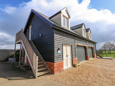 A two storey building with external wooden stairs and three dormer windows at The Attic in Blackborough End near Kings Lynn