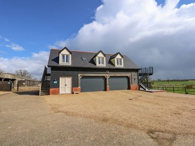 A two-story building with three dormer windows and two garage doors in a rural area at The Attic in Blackborough End near King's Lynn