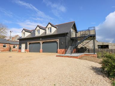 A two story building with garage doors and an external staircase at The Attic in Blackborough End near Kings Lynn