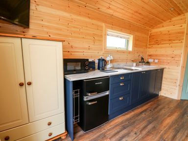 A kitchen with blue cabinets white countertop and wooden walls at Hwyl Rhayader near Llandrindod Wells