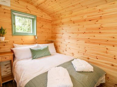 A bedroom with a double bed white pillows and robes on a bed at Hwyl Rhayader near Llandrindod Wells