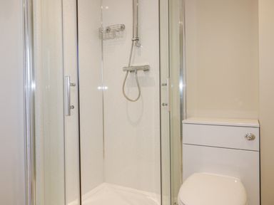 A bathroom with a glass shower enclosure and a white toilet at The Cornstore in Helland near Bodmin