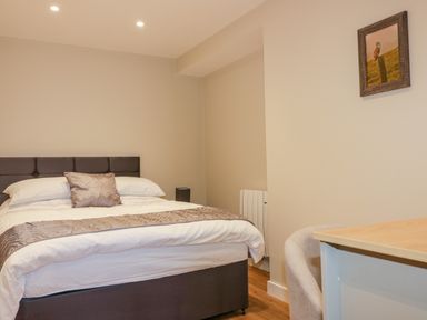 A bedroom with a bed pillow desk chair and framed picture on the wall at The Cornstore in Helland near Bodmin