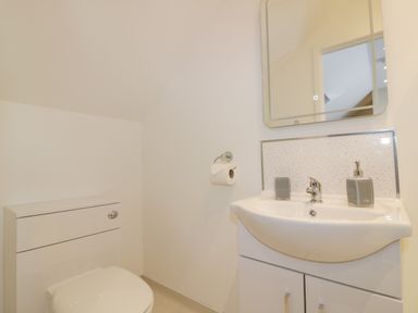 A bathroom with a toilet sink mirror and soap dispenser at The Cornstore in Helland near Bodmin