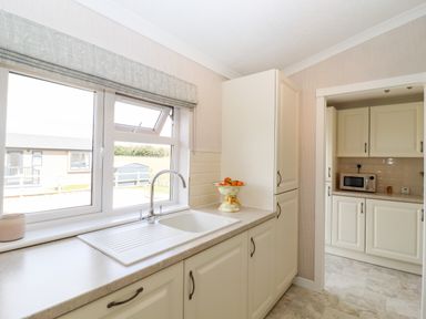 A kitchen with a sink under a window and cabinets with a fruit bowl at 12 Bucklesham Park in Bucklesham near Trimley St Martin