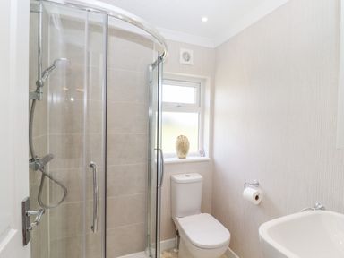 A bathroom with a shower cubicle a toilet a sink and a window with a decorative item at 12 Bucklesham Park Bucklesham near Trimley St Martin