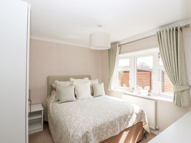 A bedroom with a bed double pillows and curtains on windows at 12 Bucklesham Park in Bucklesham near Trimley St Martin