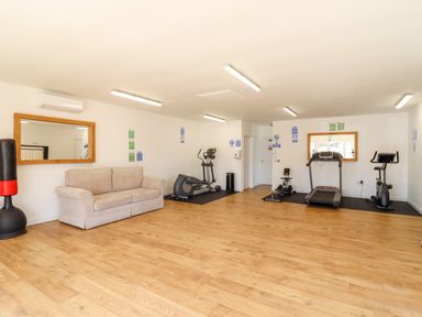 An exercise room with a sofa treadmill exercise bike punching bag and mirrors at 12 Bucklesham Park Bucklesham near Trimley St Martin