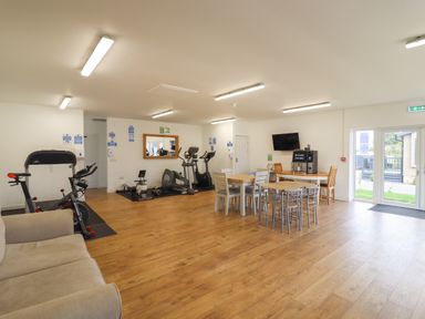 A gym area with exercise equipment and tables with chairs at 12 Bucklesham Park in Bucklesham near Trimley St Martin